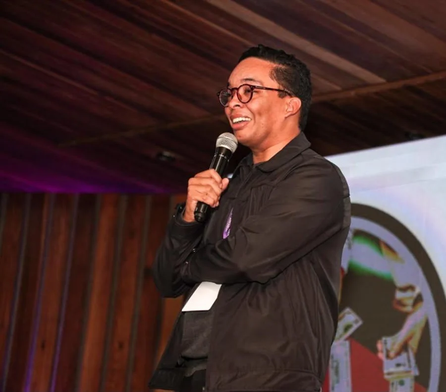 Paulo Ramos falando ao microfone no palco de um evento.